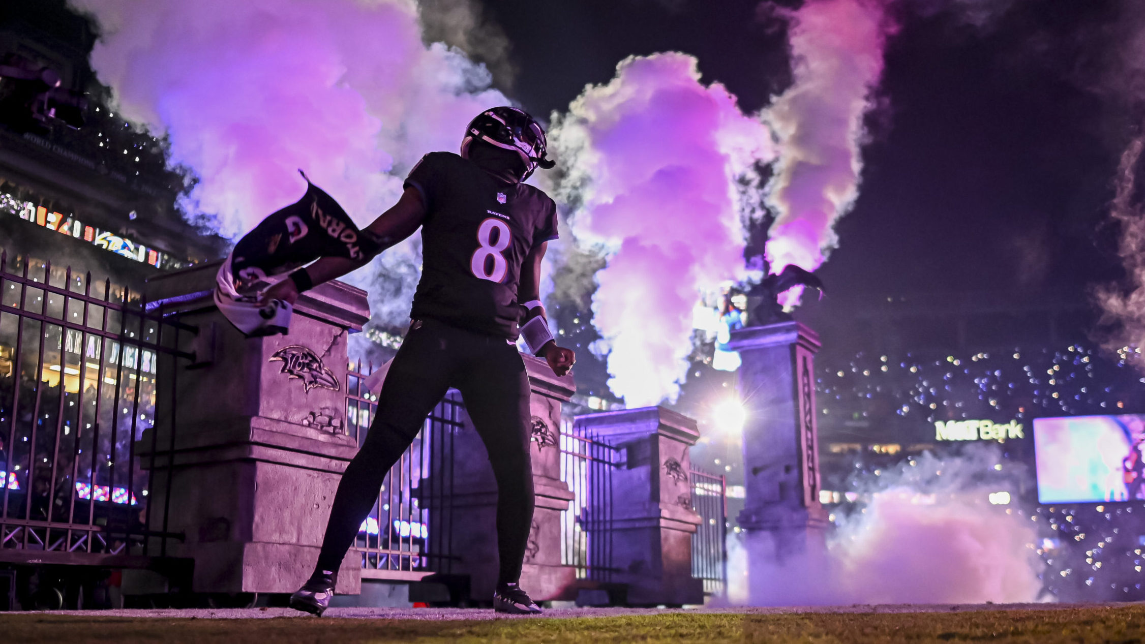 Lamar Jackson runs onto the field with purple lights flashing