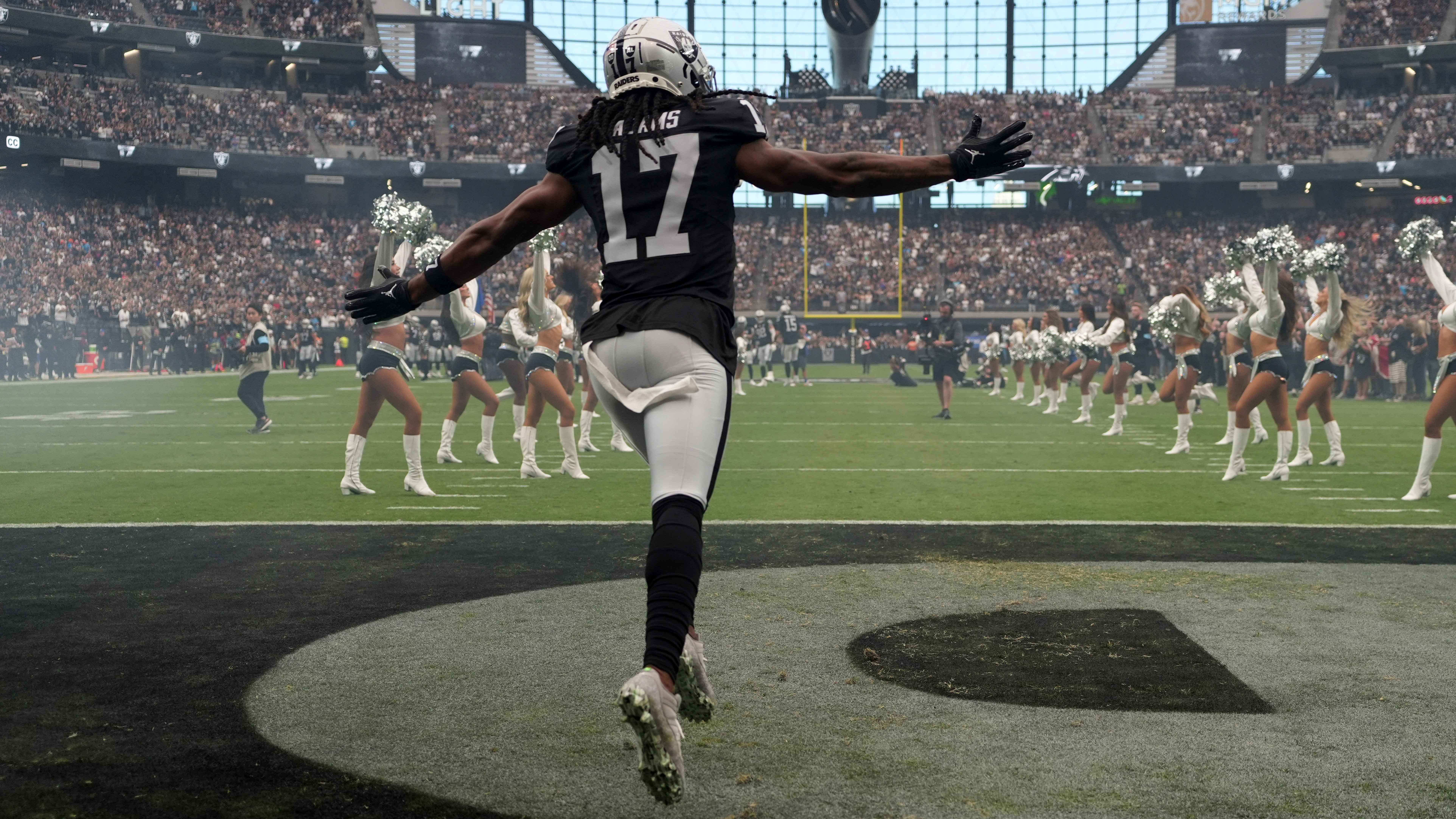 Raiders WR Davante Adams runs onto the field with his arms spread wide