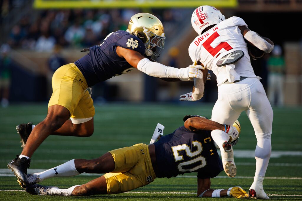 Notre Dame cornerback Benjamin Morrison and linebacker Jaiden Ausberry tackle Stanford running back Chris Davis Jr. in college football game action at Notre Dame Stadium