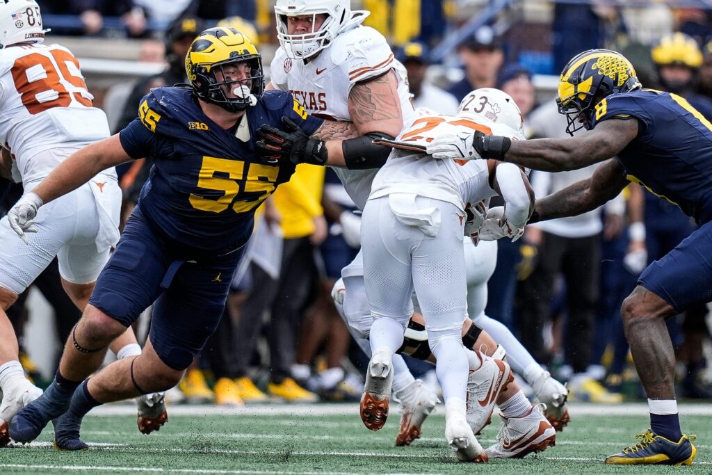 Michigan defensive lineman Mason Graham and defensive end Derrick Moore tackle Texas running back Jaydon Blue during college football game action at Michigan Stadium in Ann Arbor