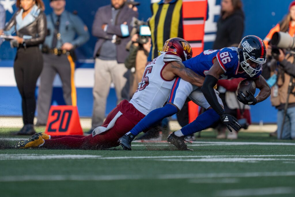 New York Giants wide receiver Darius Slayton is tackled by Washington Commanders cornerback Benjamin St-Juste after catching a pass during a game between the New York Giants and the Washington Commanders at MetLife Stadium.