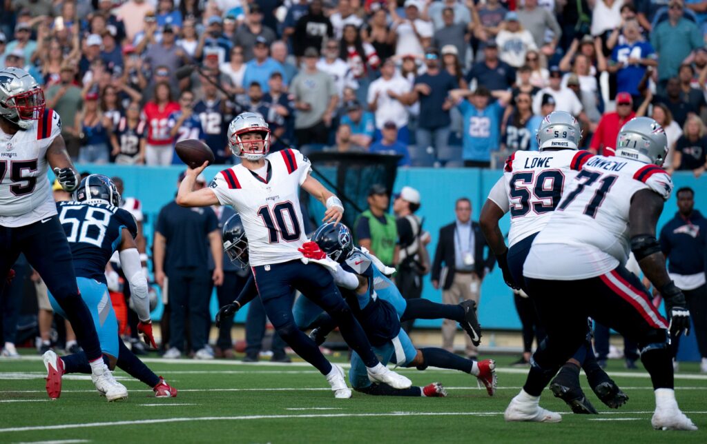 New England Patriots quarterback Drake Maye throws while in the grasp of Tennessee Titans safety Mike Brown during their game at Nissan Stadium