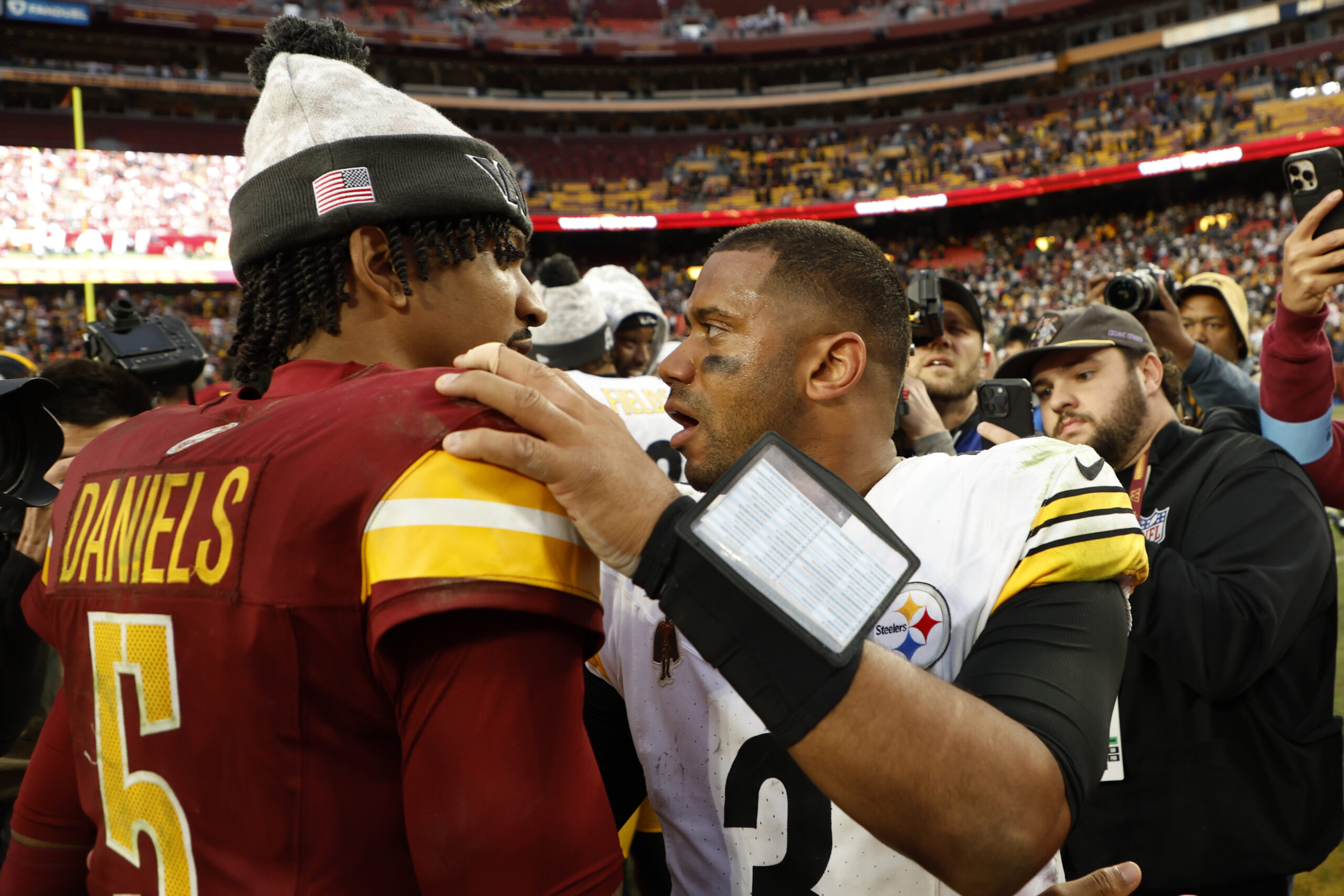 Washington Commanders quarterback Jayden Daniels (5) hugs Pittsburgh Steelers quarterback Russell Wilson (3) after their game at Northwest Stadium.