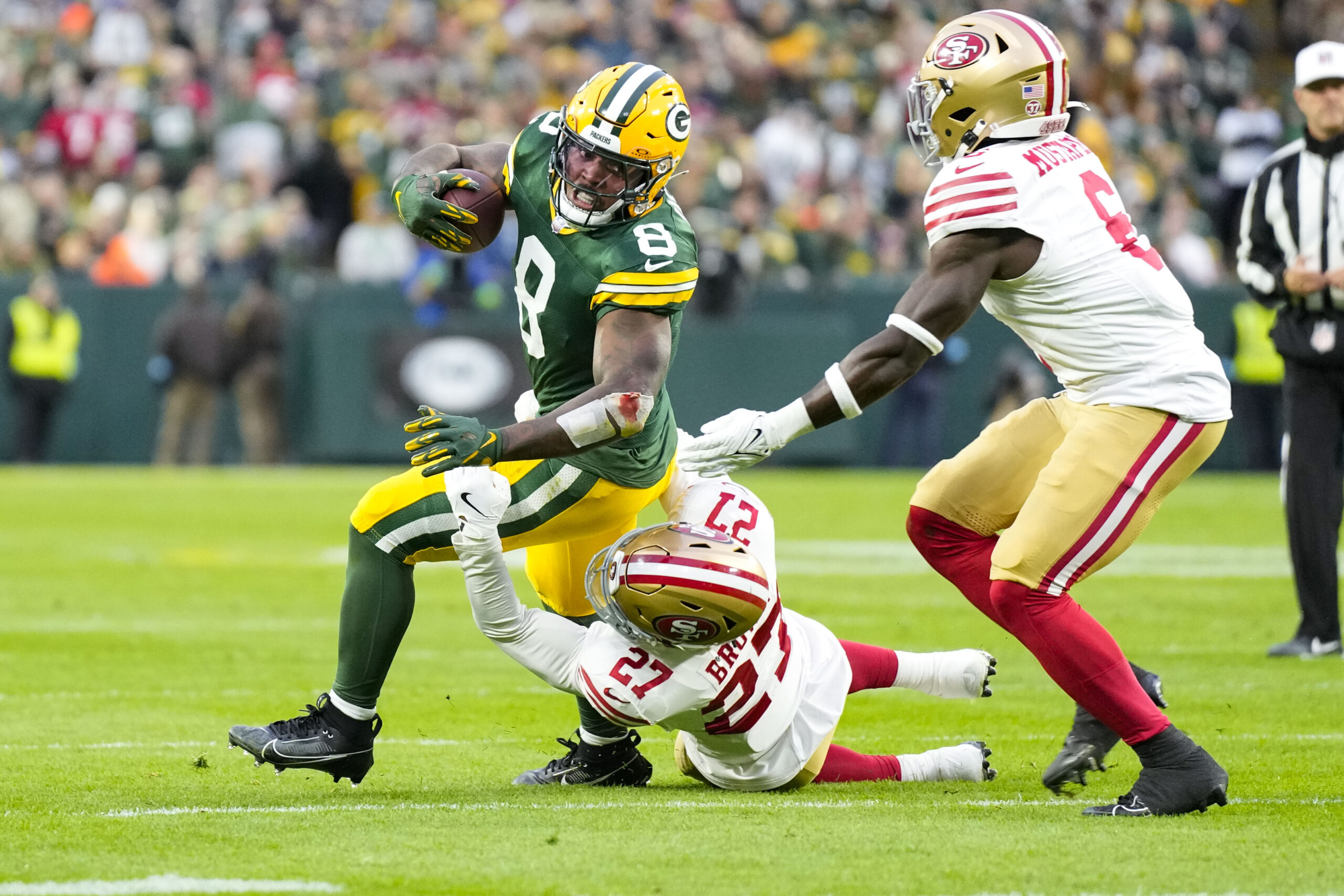 Green Bay Packers running back Josh Jacobs (8) is tackled by San Francisco 49ers safety Ji'Ayir Brown (27) during the first quarter at Lambeau Field.