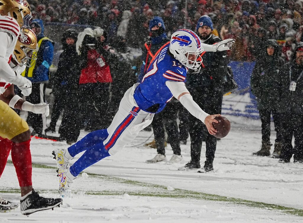 Bills Josh Allen leaps to the end zone in a nine-yard touchdown run after getting the ball passed back to him from Amari Cooper during second half action of their home game against the San Francisco 49ers