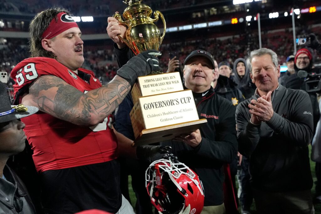 Georgia coach Kirby Smart hands the governor cup to Georgia offensive lineman Tate Ratledge (69) after Georgia won a NCAA college football game against Georgia Tech in overtime. 