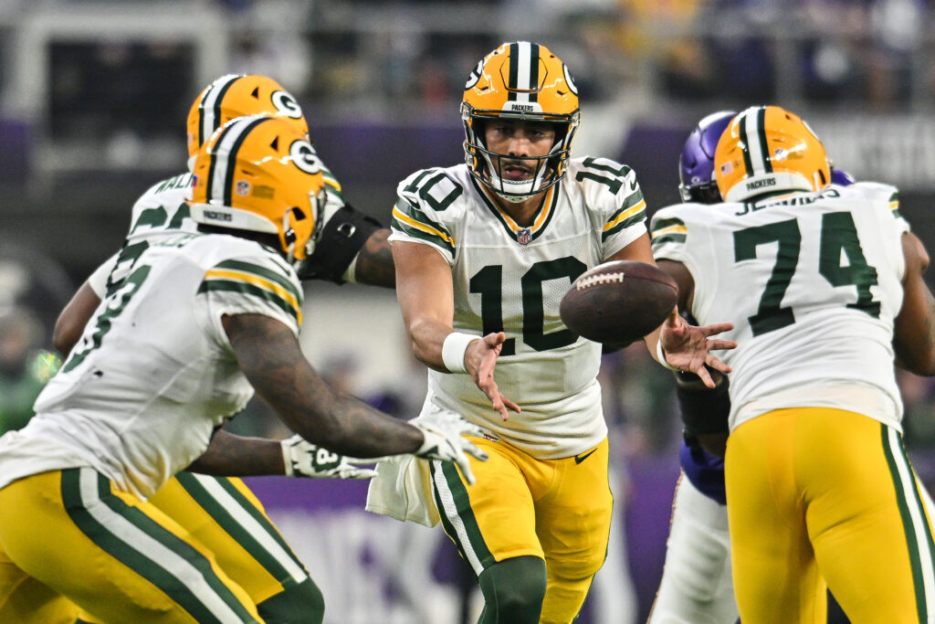 Green Bay Packers quarterback Jordan Love (10) tosses the ball to running back Josh Jacobs (8) against the Minnesota Vikings during the second quarter at U.S. Bank Stadium.