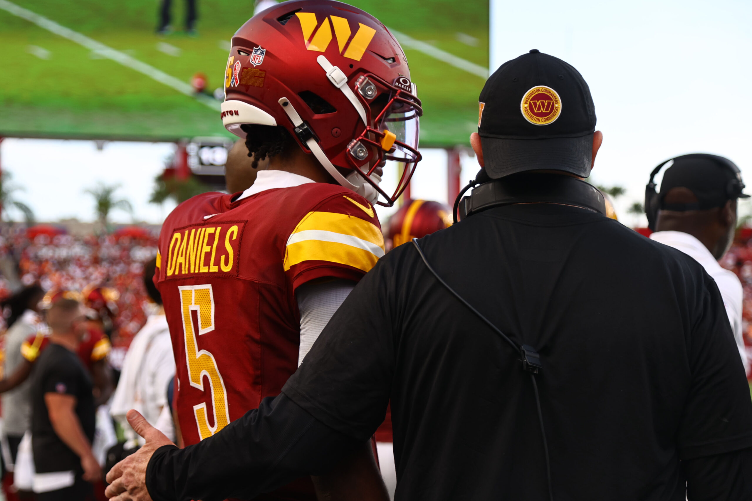 Washington Commanders quarterback Jayden Daniels (5) talks with head coach Dan Quinn during the second half against the Tampa Bay Buccaneers.