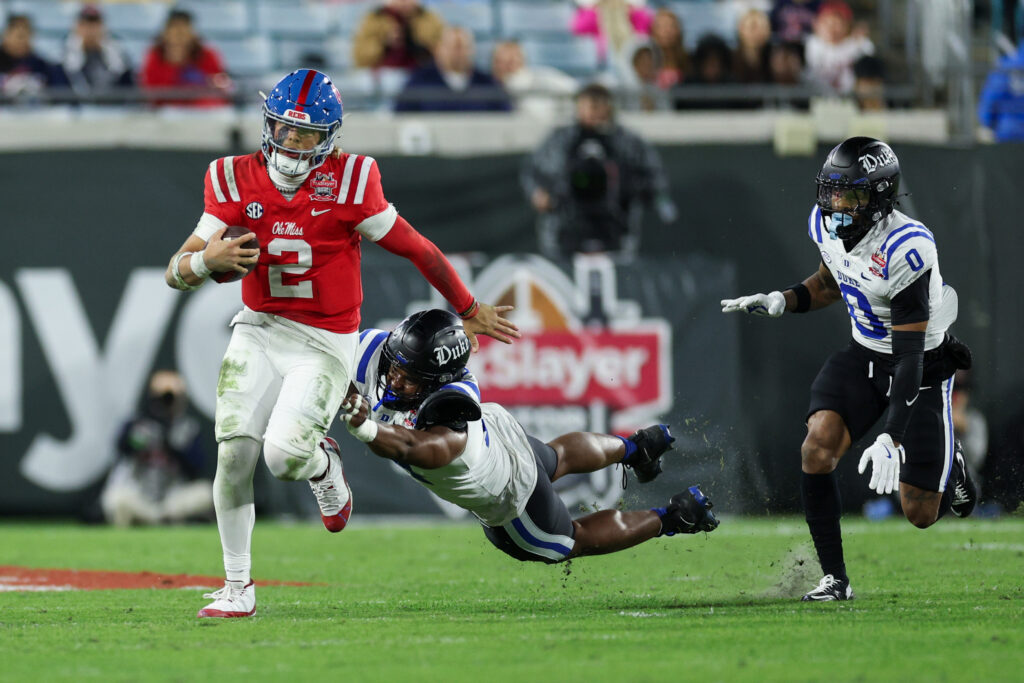 Mississippi Rebels quarterback Jaxson Dart (2) runs with the ball chased by Duke Blue Devils defensive end Michael Reese (14) in the second quarter during the Gator Bowl at EverBank Stadium.