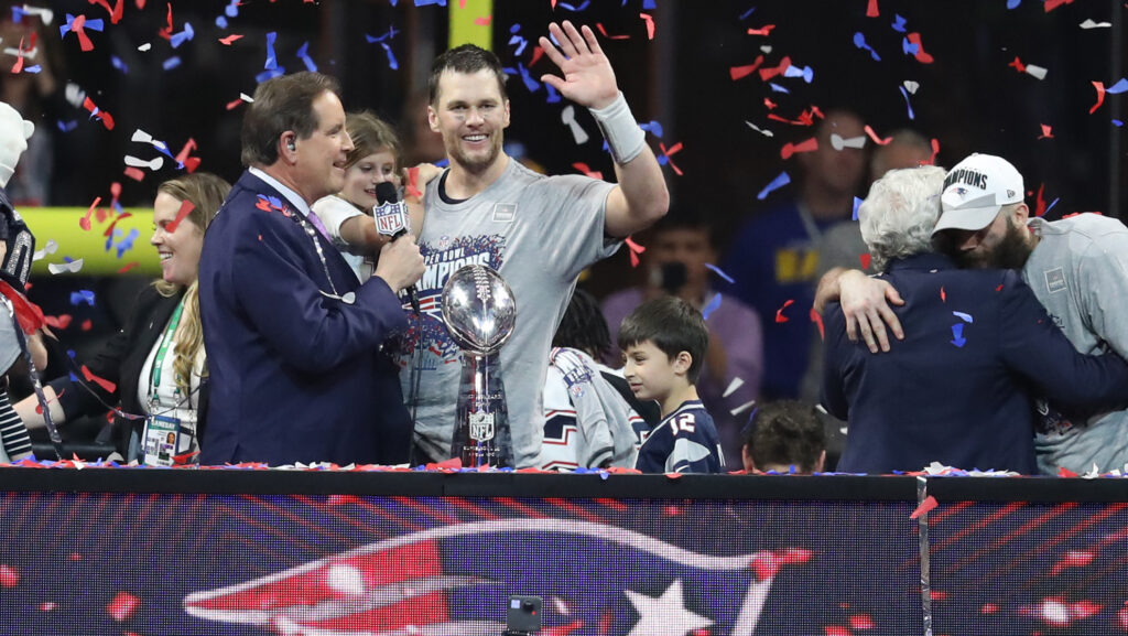 New England Patriots quarterback Tom Brady (middle) talks with Jim Nantz (left) while holding daughter Vivian as Patriots owner Robert Kraft embraces MVP wide receiver Julian Edelman (right) after defeating the Los Angeles Rams in Super Bowl LIII.