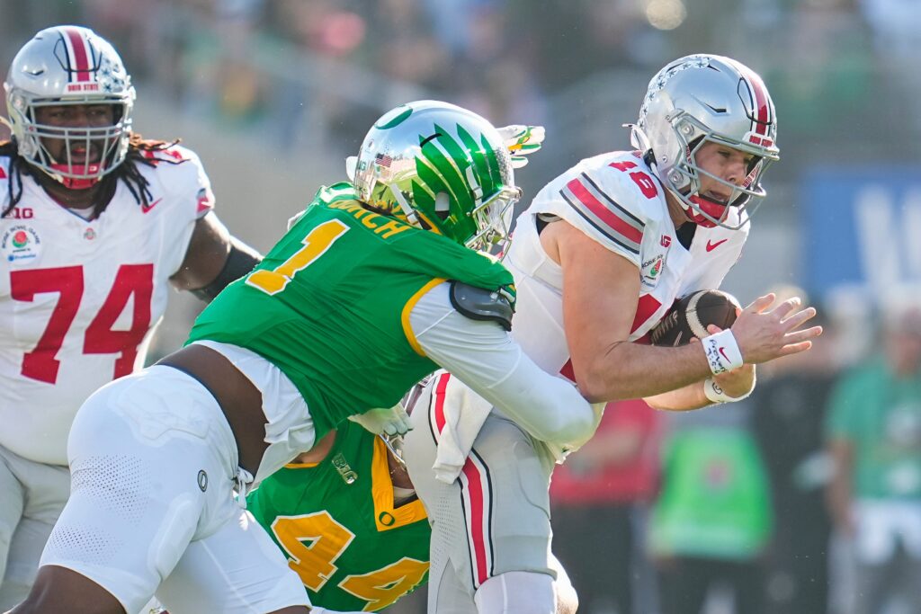 Ohio State Buckeyes quarterback Will Howard (18) runs through Oregon Ducks defensive end Jordan Burch (1) during the first half of the College Football Playoff quarterfinal at the Rose Bowl in Pasadena, Calif.